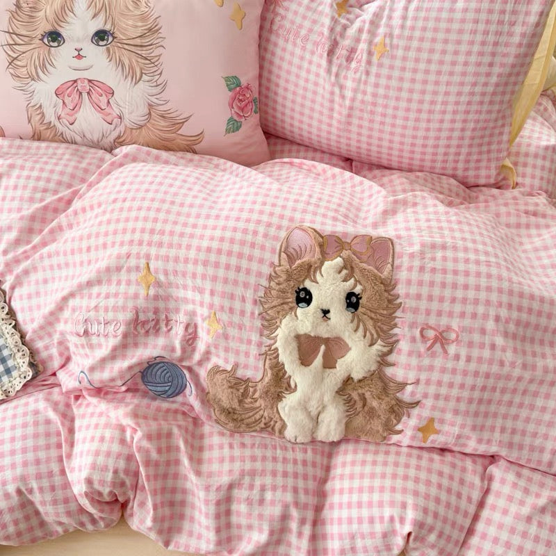 Pink checkered bedding set with a cute animal design on a pillow and plush toy.