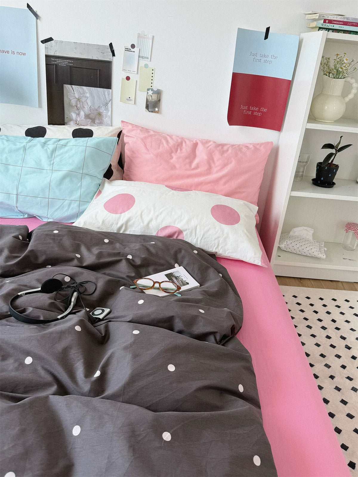 Front view of pink and gray bedding with blue checks, pink dots, black dots and a solid pink pillow.