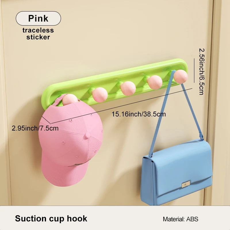 Suction cup hook with pink traceless sticker holding a pink cap and blue bag on a beige wall.