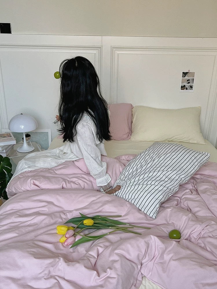 Pink jersey bedding set photographed from the side with a cat on the bed