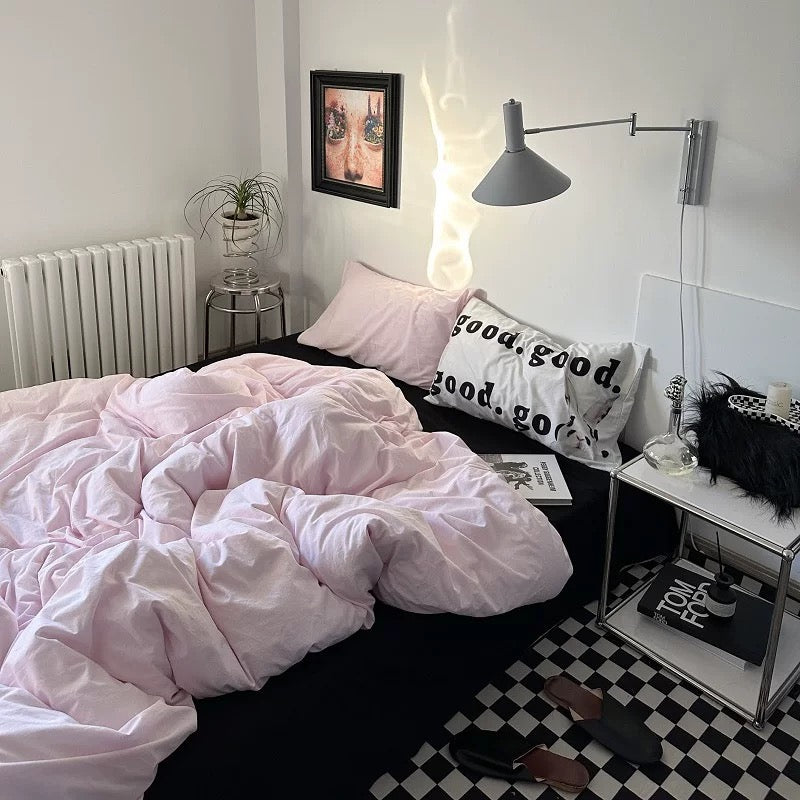 Minimalist pink bedding set styled in a cozy modern bedroom with typography pillows.