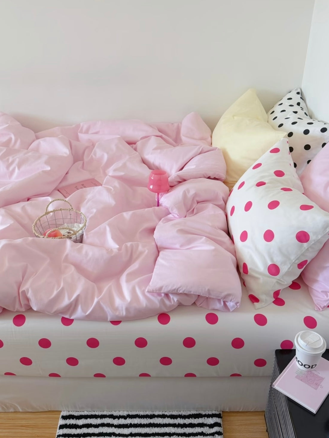 Pink polka dot bedding set with a plain pink cover, yellow and dotted pillows, and a white sheet with fuchsia dots.