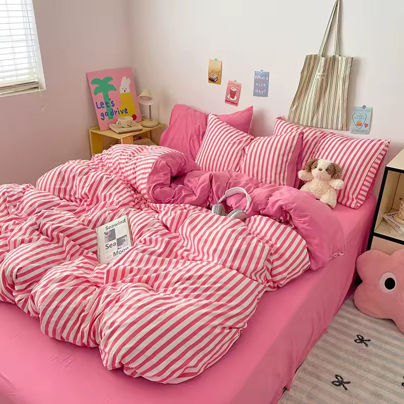 Pink and white striped bedding set on a bed in a room with decorative elements.