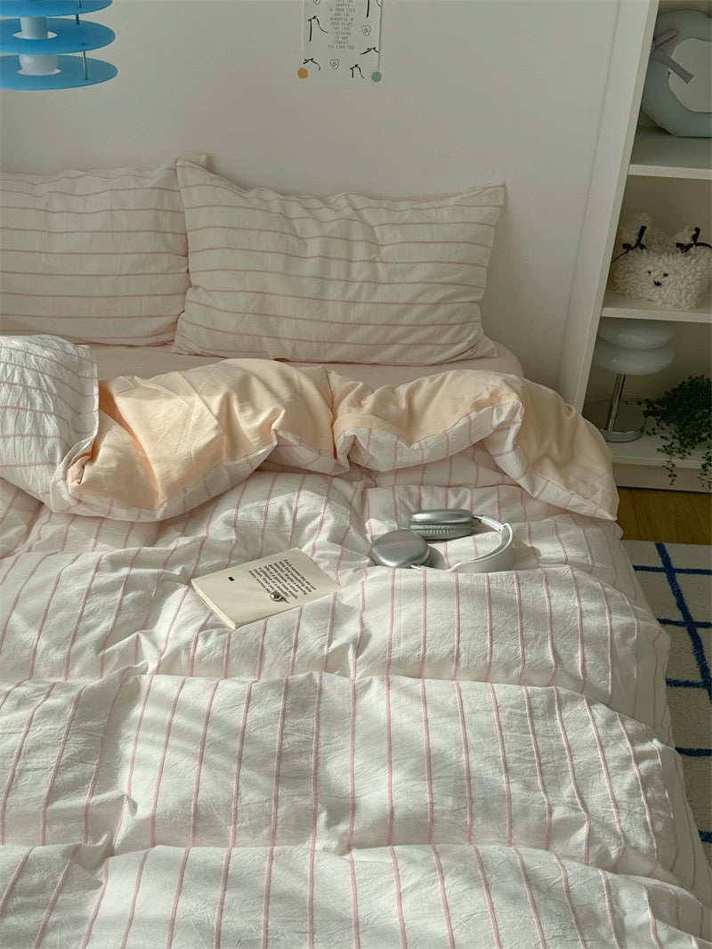 Bed with striped bedding and pillows in a room setting.