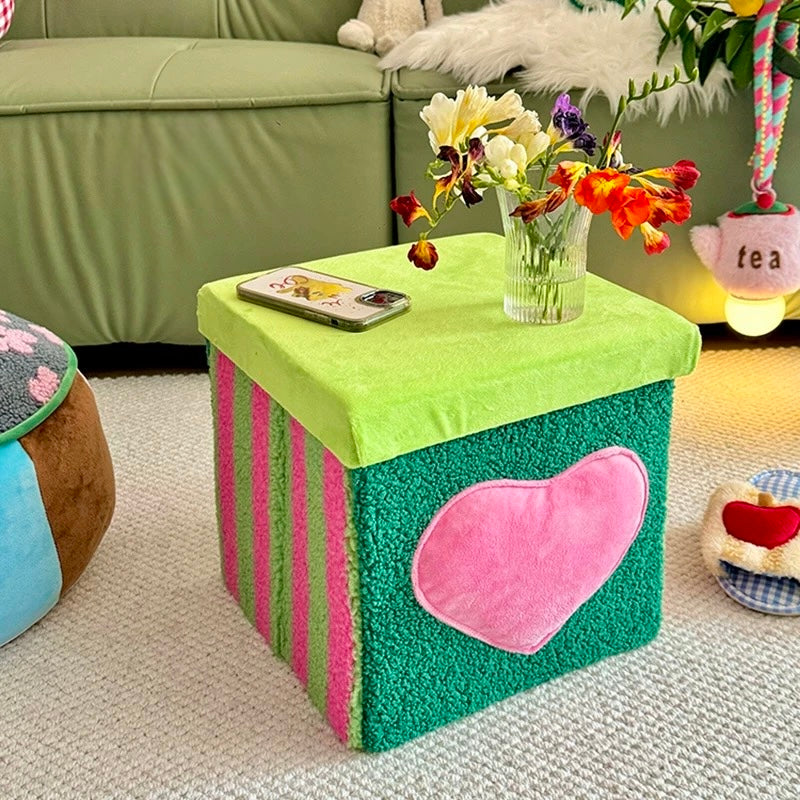 Green velvet storage stool used as a side table with flowers