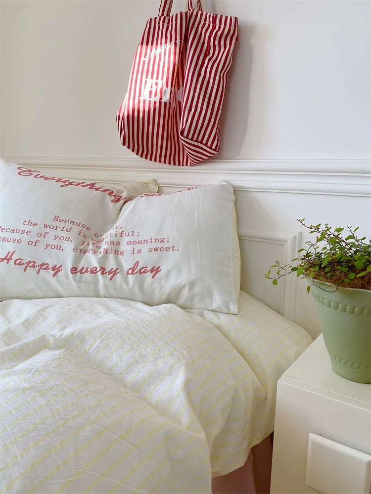Bedroom with pillows and a red and white striped bag on the headboard