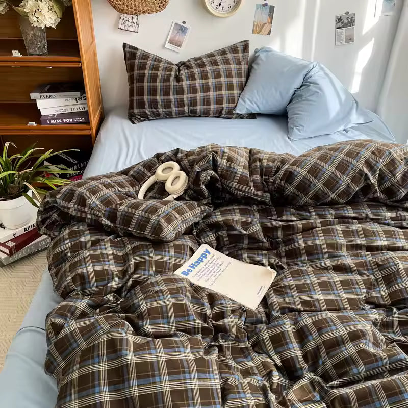 Plaid comforter on a bed with pillows and a bookshelf in the background