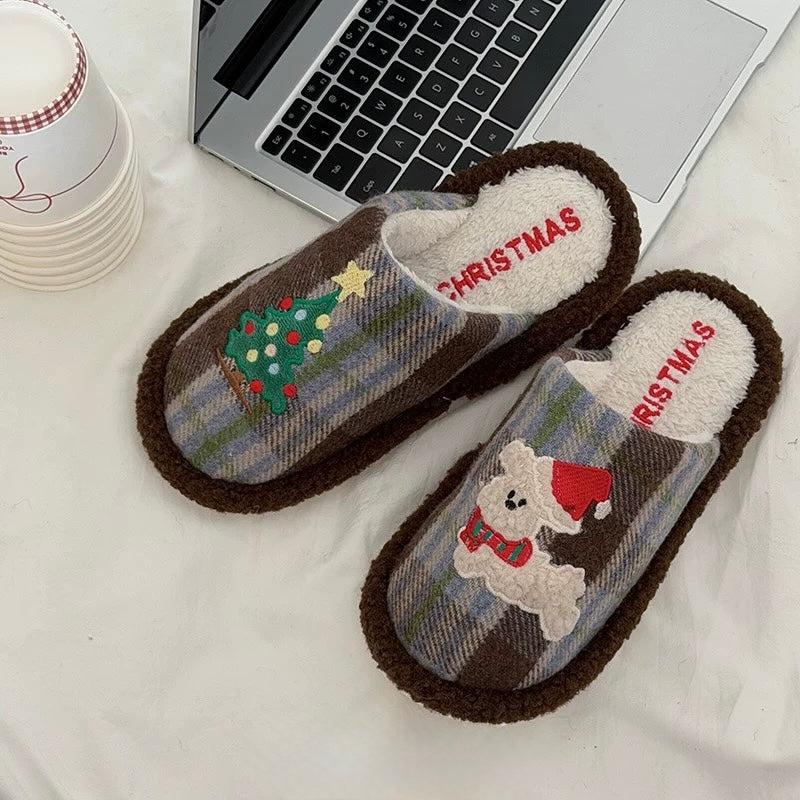 Brown plaid Christmas slippers with tree and puppy motifs beside a laptop