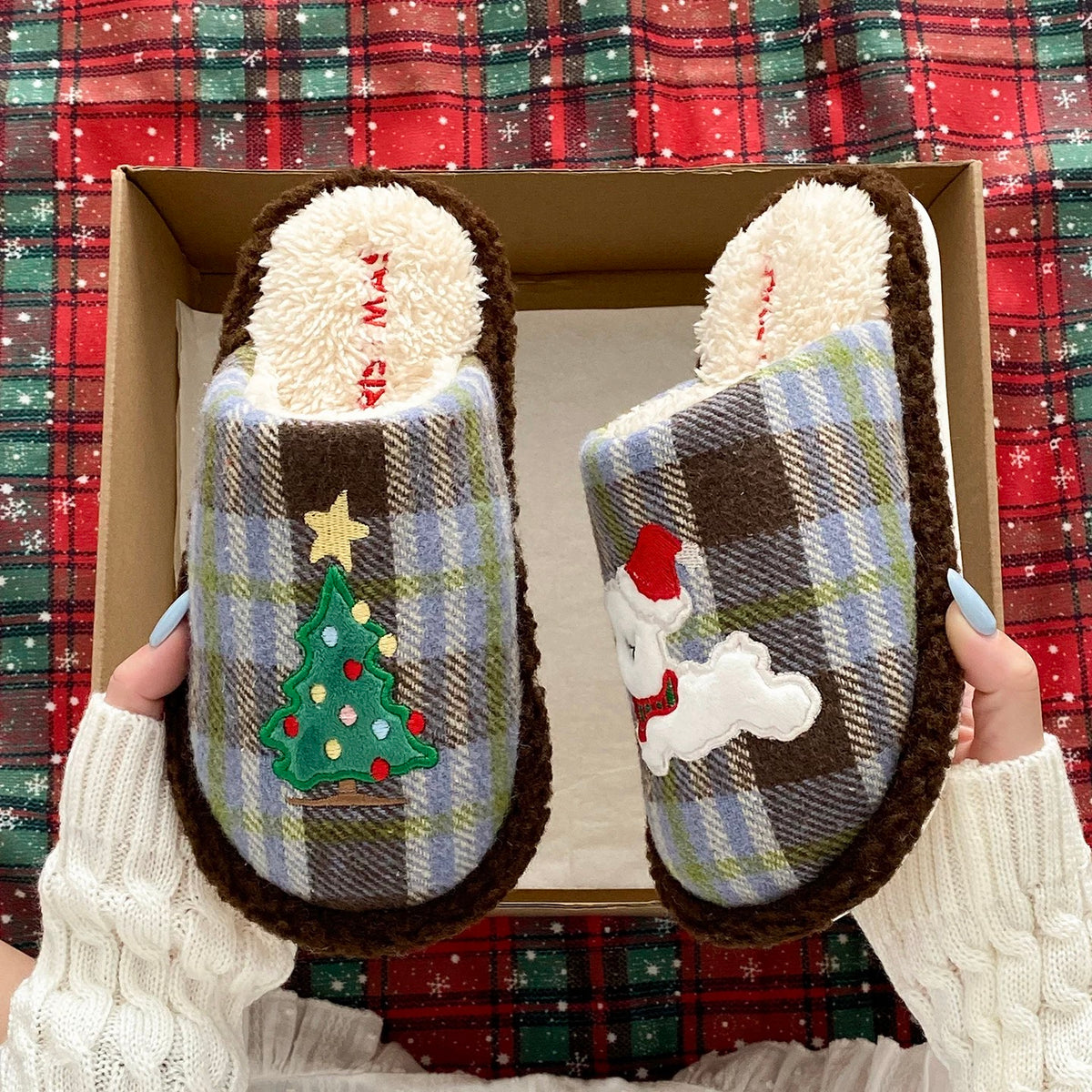 Blue plaid Christmas tree slippers with puppy motif held against a red tartan background
