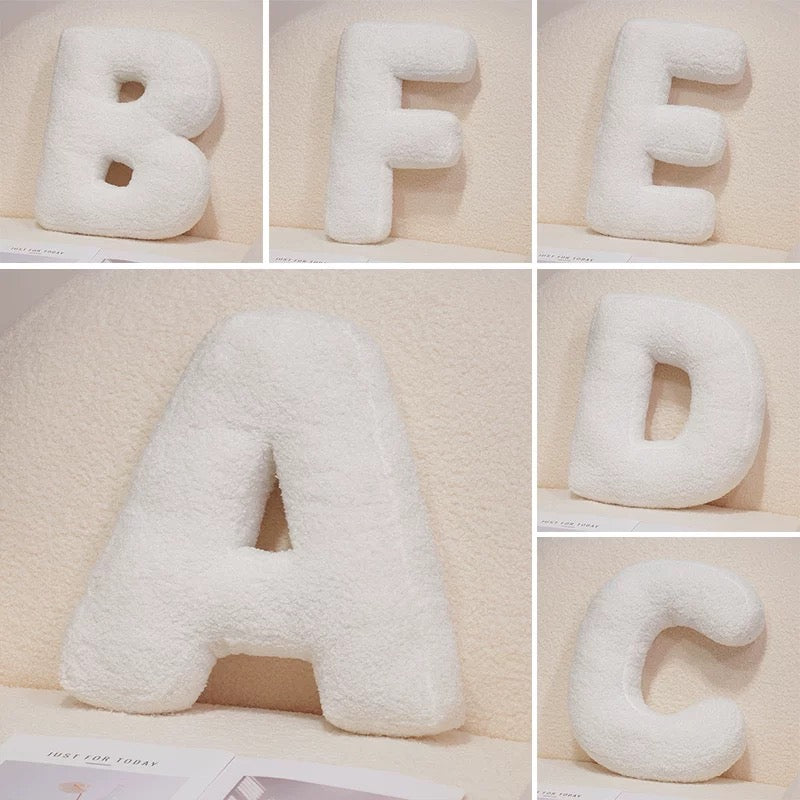 Set of letter-shaped cushions spelling 'BEAD' on a neutral background