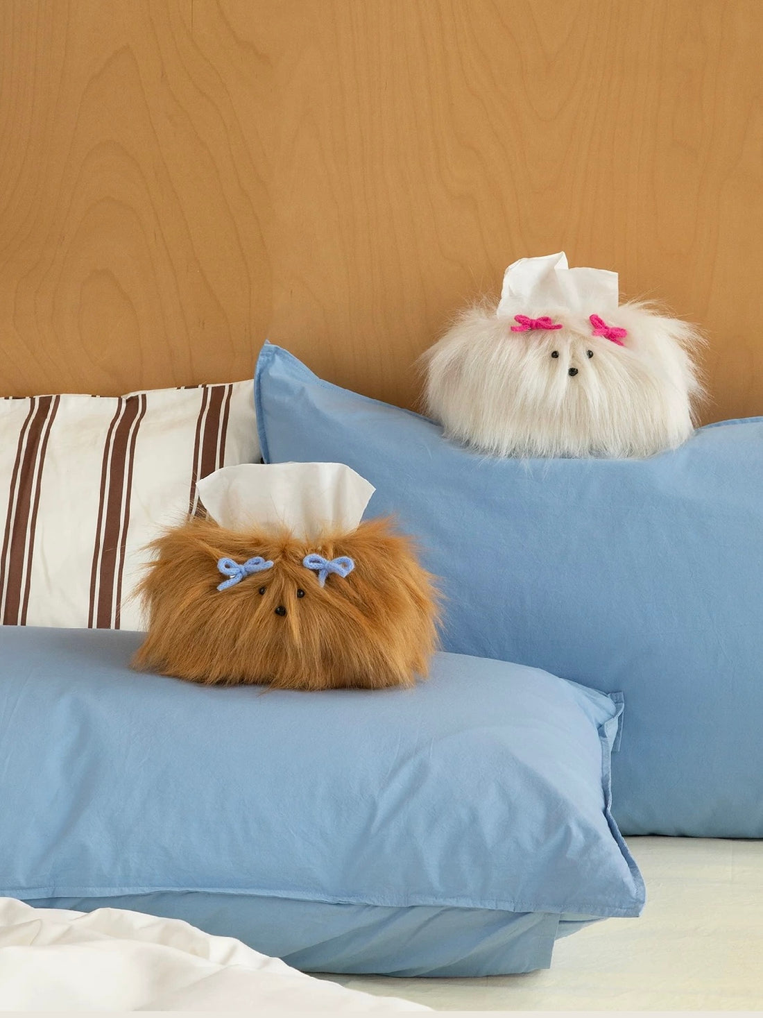 Plush tissue box covers in Cream White and Caramel sit on blue pillows, with pink and blue bows above their faces.