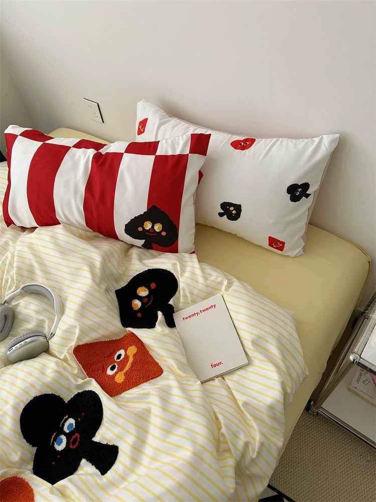 Cozy playing card-themed bedding set on bed, showing embroidered details and soft striped fabric for stylish bedrooms.