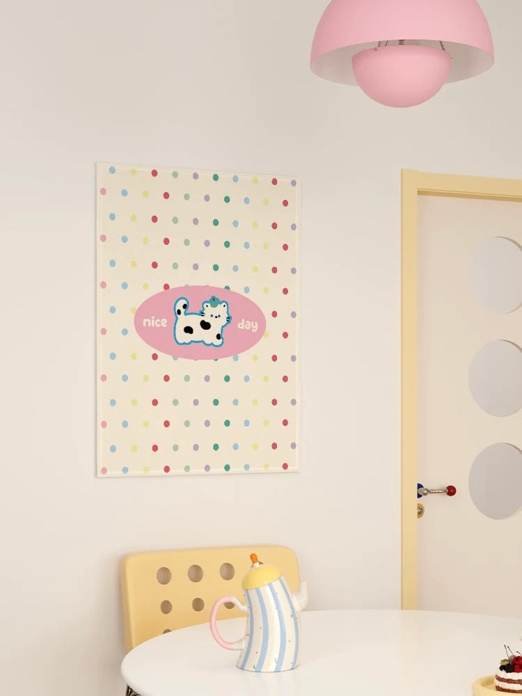 A polka dot cat tapestry shows a spotted cat inside a pink oval on a cream ground with small colored dots.