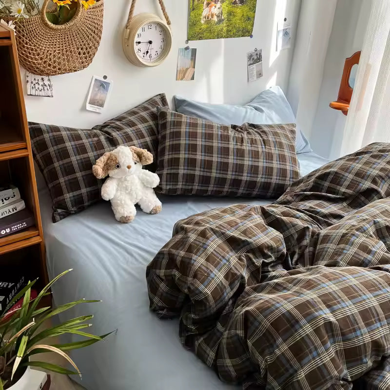 Bed with plaid bedding and pillows, teddy bear, and decorative items in a room.