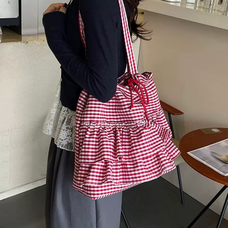 Person holding a red and white checkered bag in an indoor setting