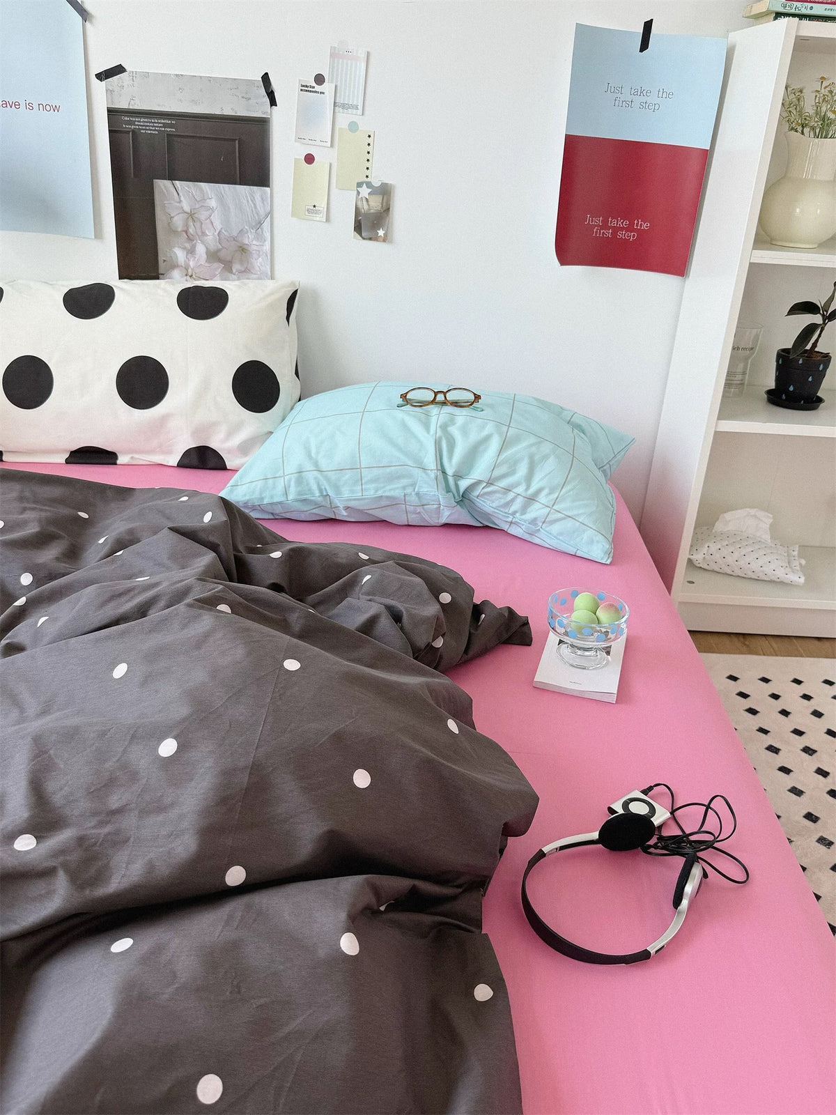 Preppy bedding with a blue checked pillow beside large black dots on white above the small dotted cover.