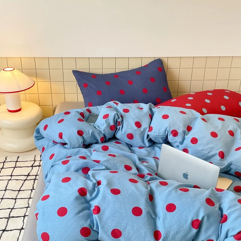 Preppy blue and red polka dot duvet cover set displayed on a neatly styled dorm room bed with matching pillowcases.
