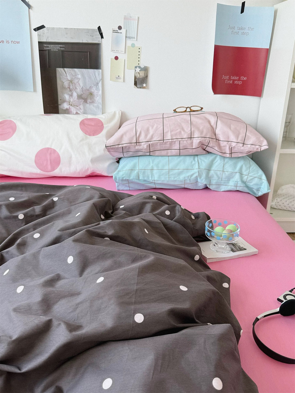 Preppy pink polka dot bedding set with a dark dotted cover, a pink sheet and stacked dotted and checked pillows.