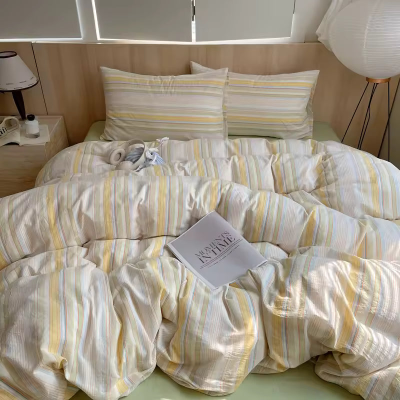 Striped bedding on a bed with a book titled 'Woman in the World' on top, in a bedroom setting.