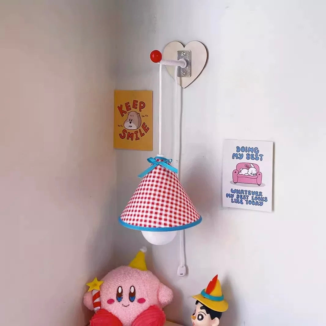 Children's lamp with checkered shade, clock, and figurine on a table against a wall with posters.