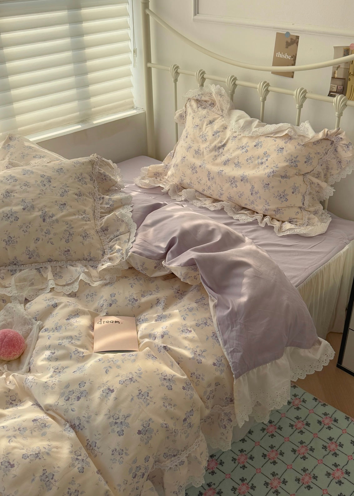 Floral bedding set on a bed with a white headboard and light-colored walls.
