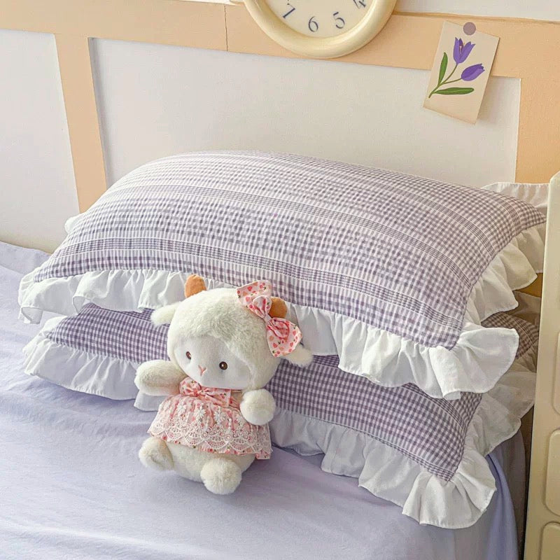 Checkered pillow with ruffles and a plush toy on a bed