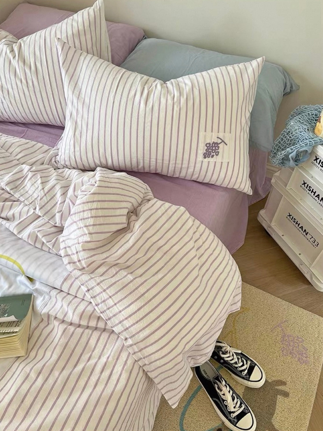 Close bedroom view of striped duvet cover folds and matching purple applique pillowcases.