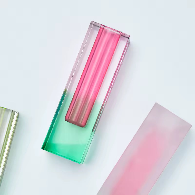 Gradient glass vases in pink and green on a light gray background