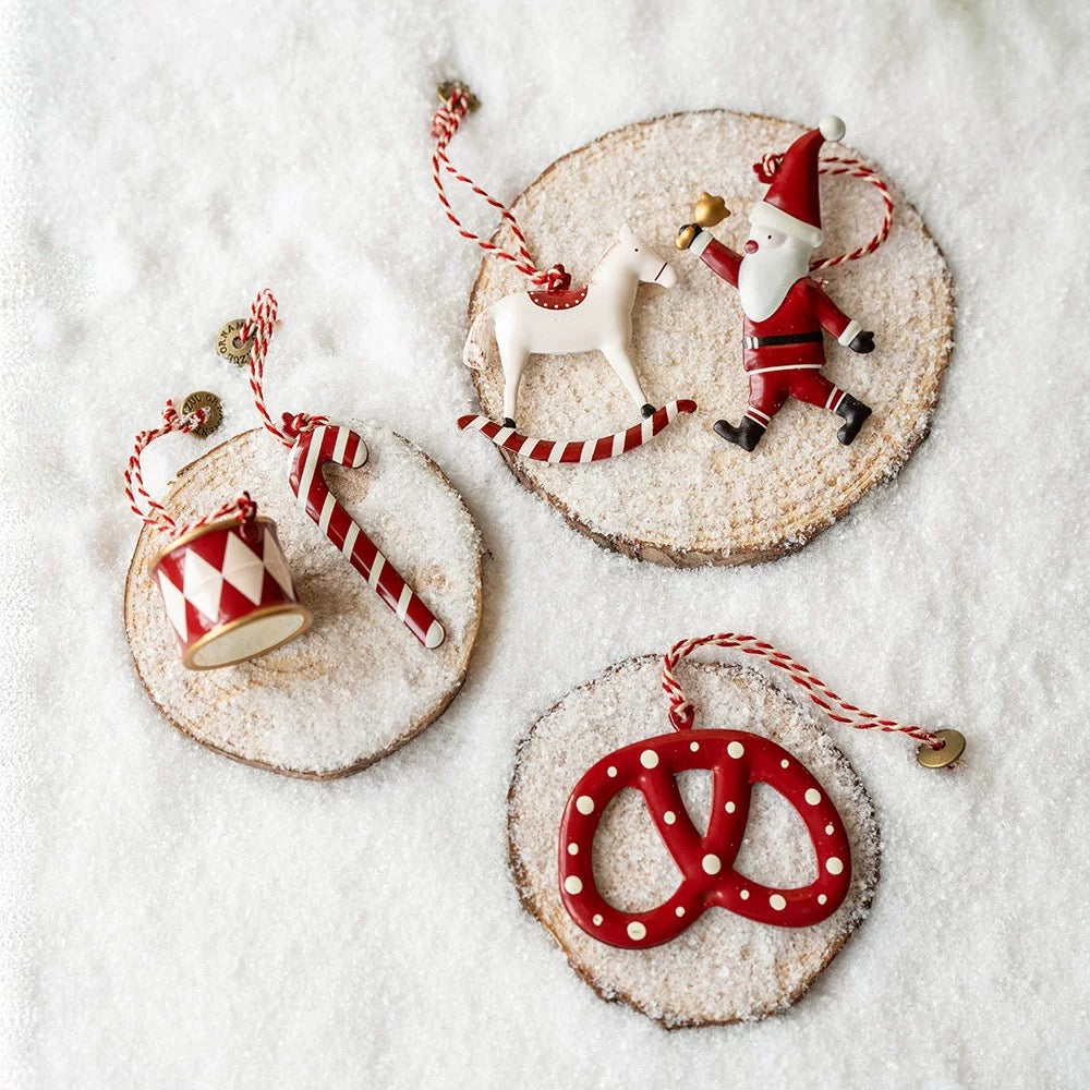 Red Christmas ornaments include a Santa with a gift, a rocking horse, a patterned drum and a dotted pretzel.