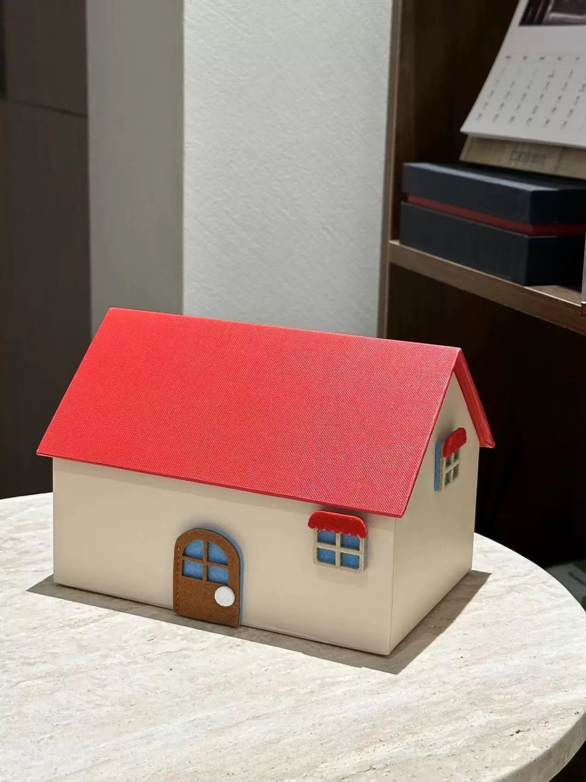 Red and cream house shaped tissue box cover on a tabletop