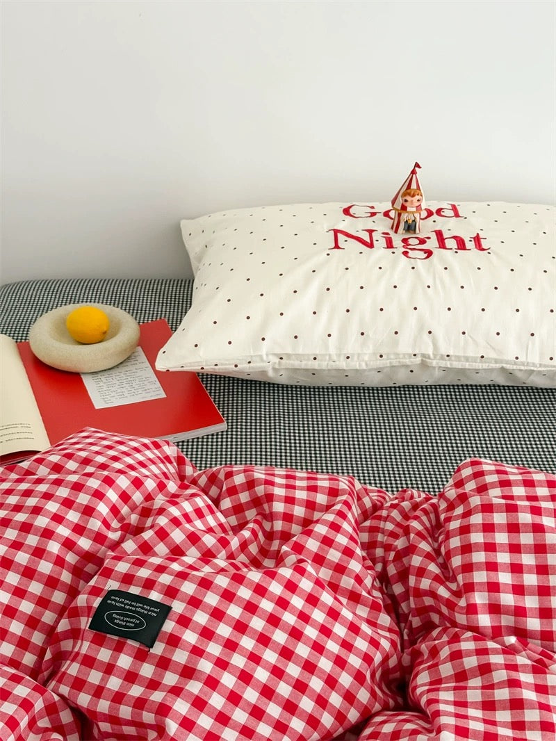 Red and white checkered duvet on a bed with a pillow that says 'Good Night'.