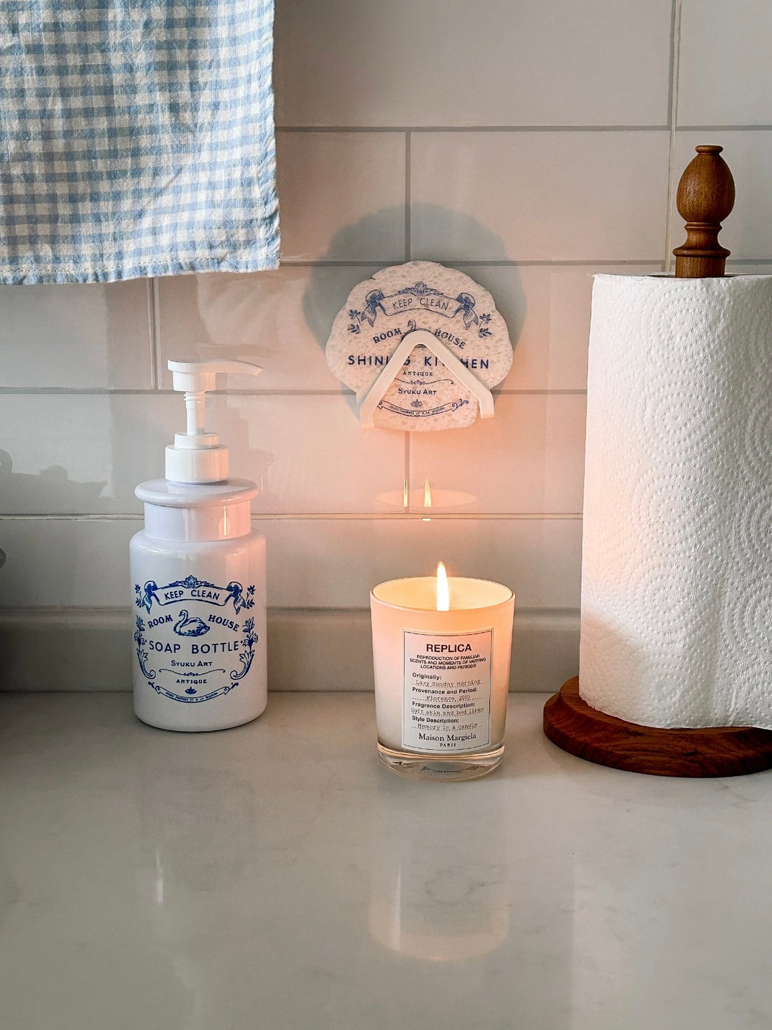 The floral soap dispenser stands beside a matching scalloped sponge, with blue swan artwork on white.