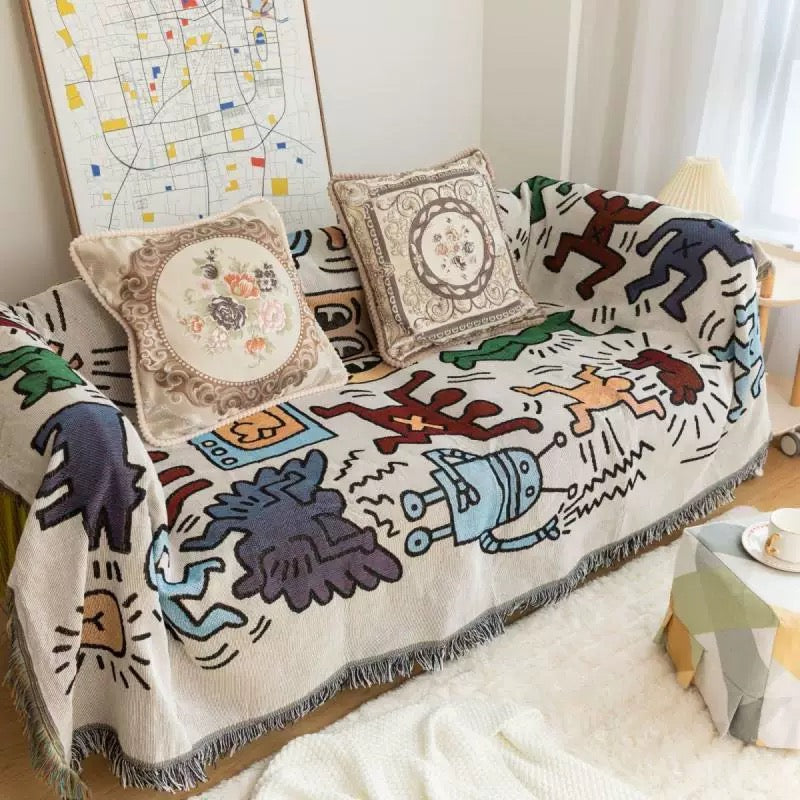 Colorful jacquard throw blanket with retro figures draped over a couch in a boho-style living room