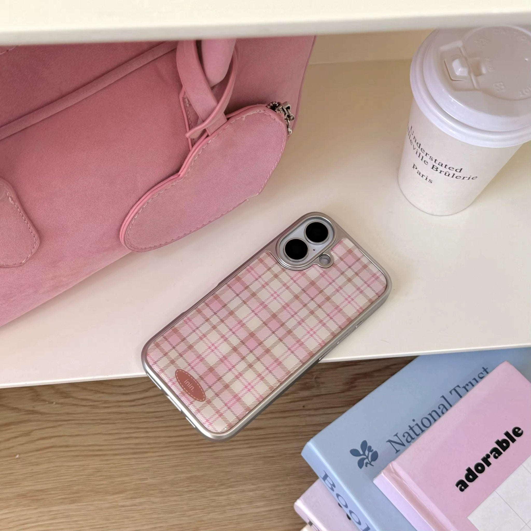 Pink aesthetic phone case lying next to pastel books and a latte cup for cozy desk setup