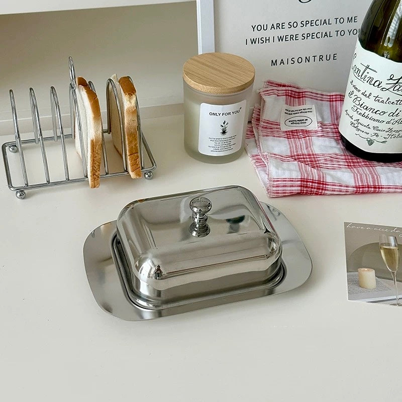 Butter dish on a kitchen counter with bread, a candle, and a bottle of wine.