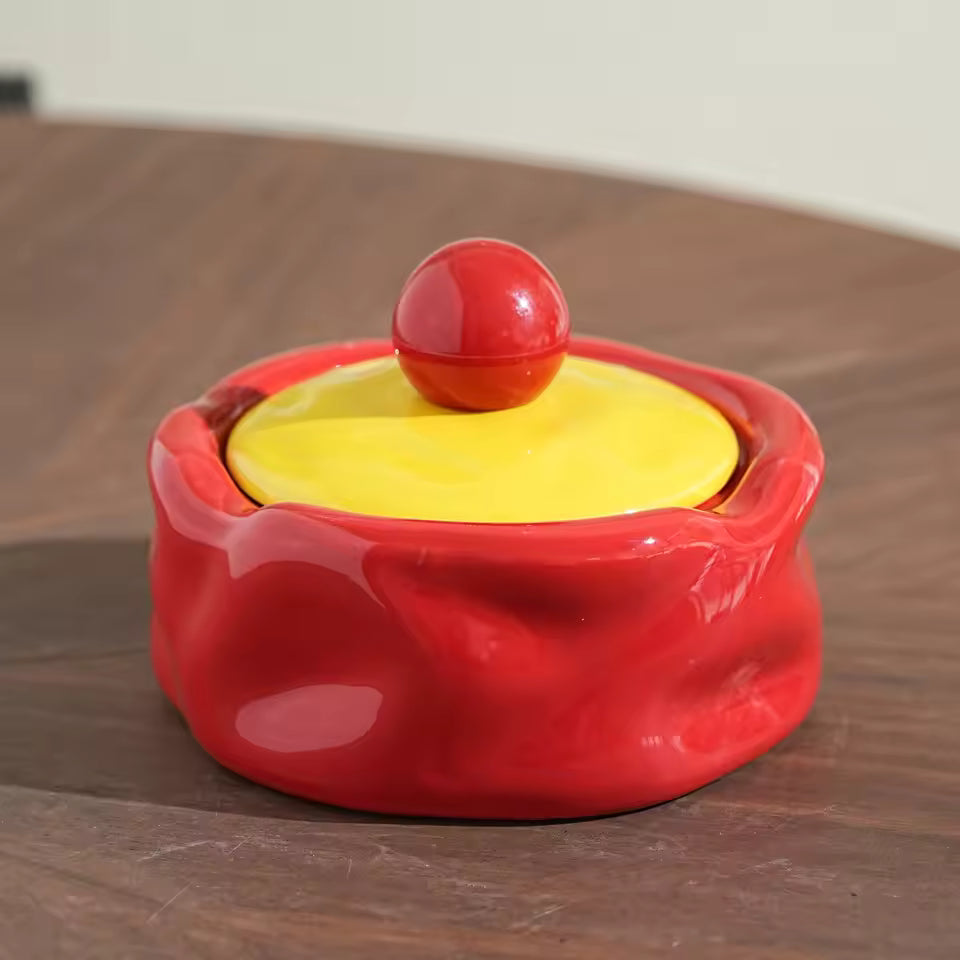 Red and yellow container with a ball on top on a wooden surface