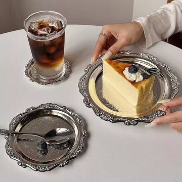 Slice of cheesecake with a glass of iced coffee on a decorative silver tray.