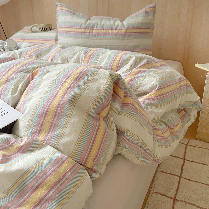 Striped bedding on a bed with a wooden headboard