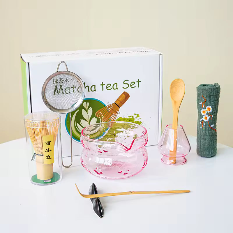 Matcha tea set with various tools and a branded box on a white surface.