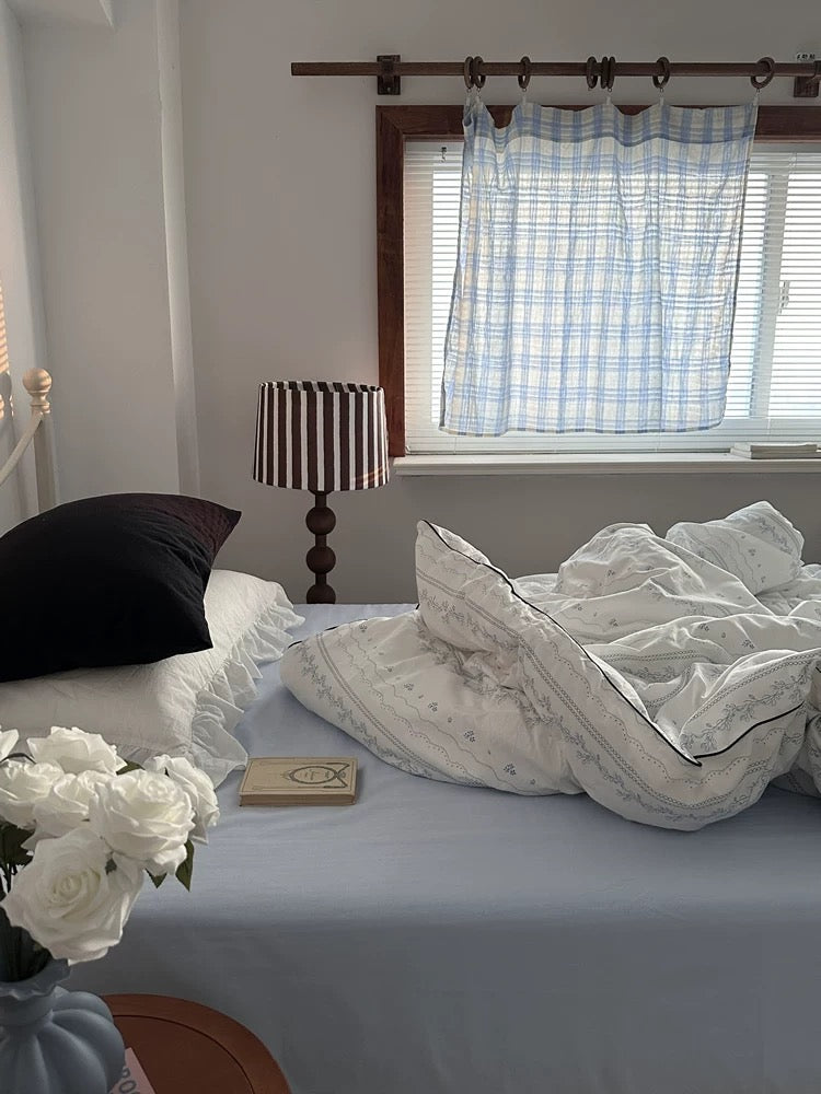 Bedroom with a bed, lamp, and window with curtains