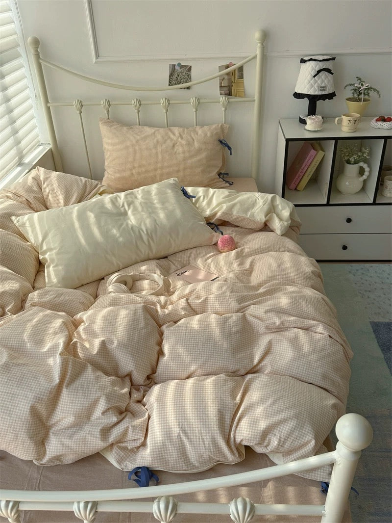 Neatly made bed with beige bedding in a bright bedroom.