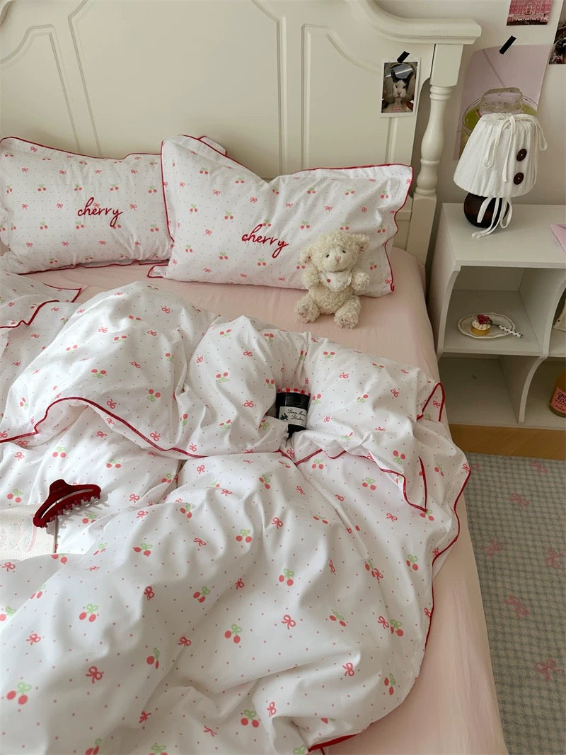 Bed with cherry-themed bedding and pillows in a bedroom setting.