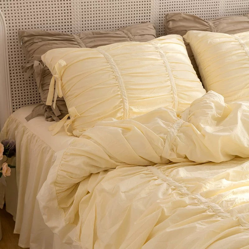 Yellow ruffled comforter on a bed with matching pillows against a neutral headboard.