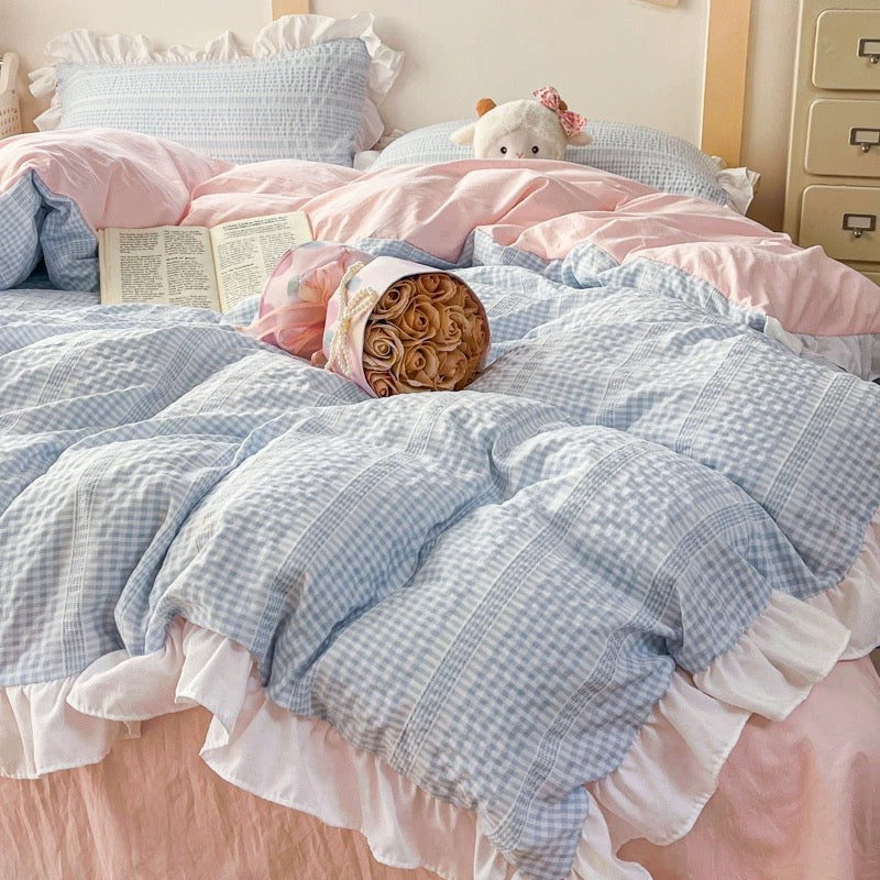 Bed with blue and pink checkered bedding and a teddy bear.