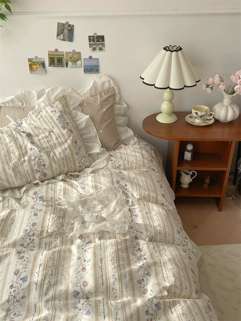 Bedroom with floral bedding, lamp, and small table with items.
