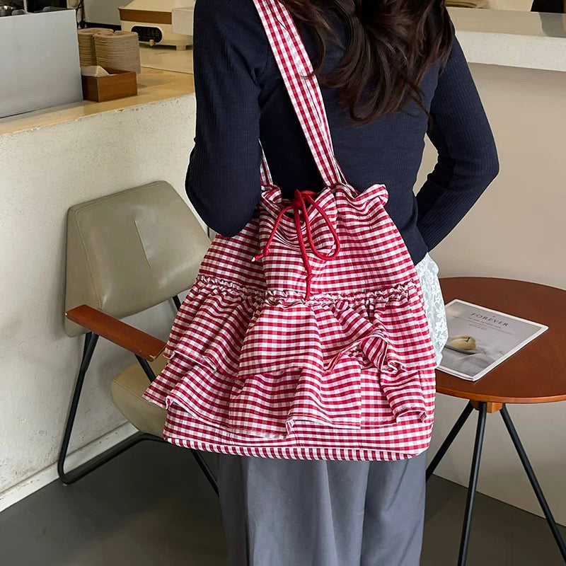 Person wearing a red and white checkered apron in an indoor setting