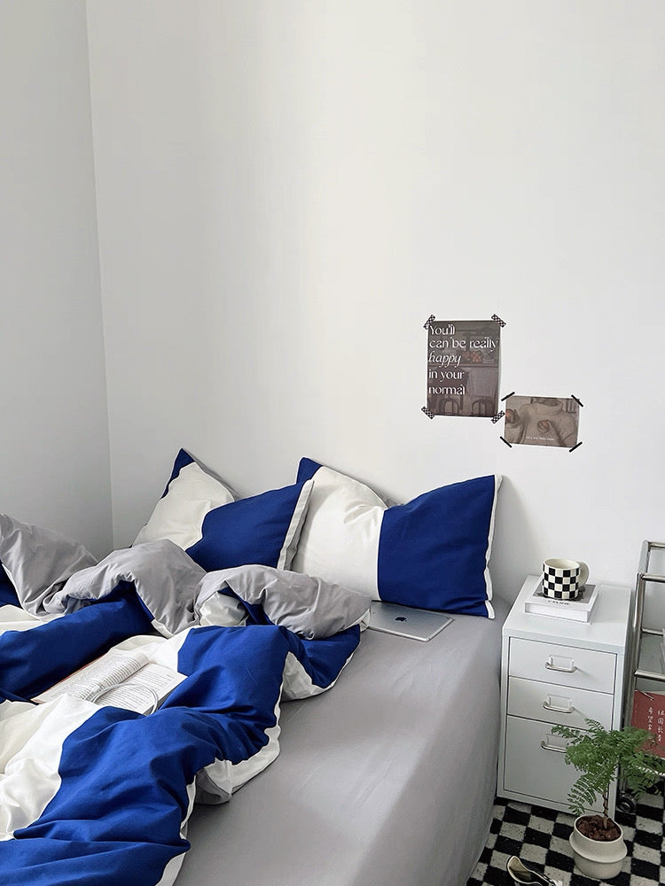 Bedroom with blue and white bedding, nightstand, and wall art.