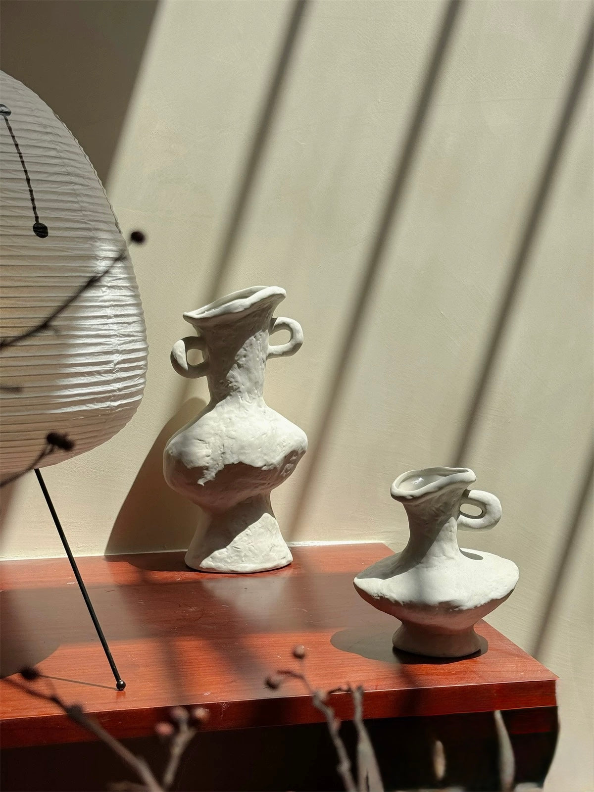 Two ceramic vases on a wooden surface with a neutral background
