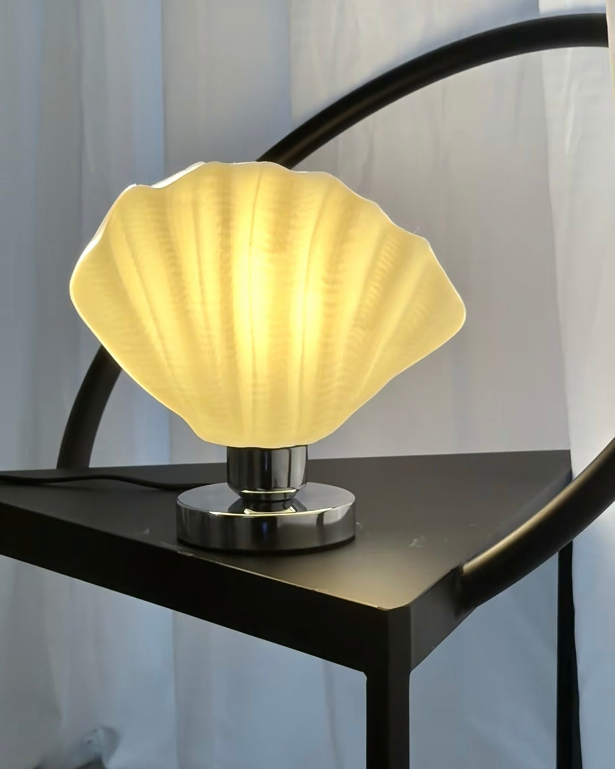 Decorative white shell shaped table lamp placed on bedroom nightstand with cozy evening lighting