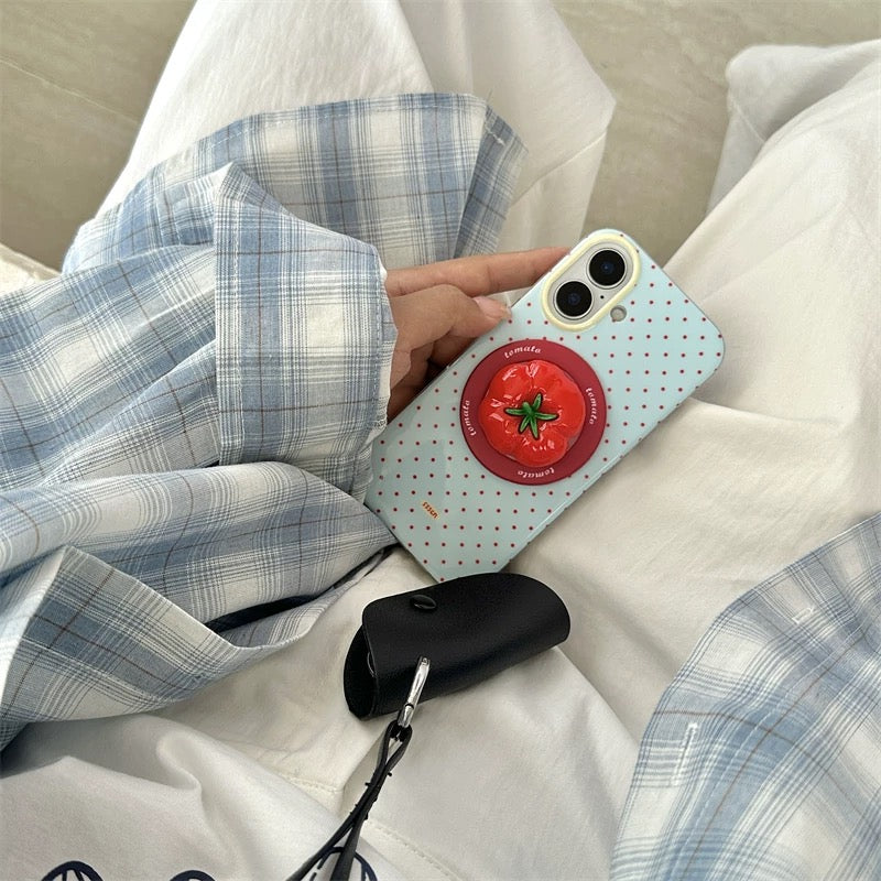 Phone case with tomato design held by a person on a white surface